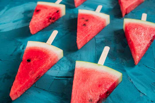 a view from above on the lobules of watermelon on sticks laid out on a blue background