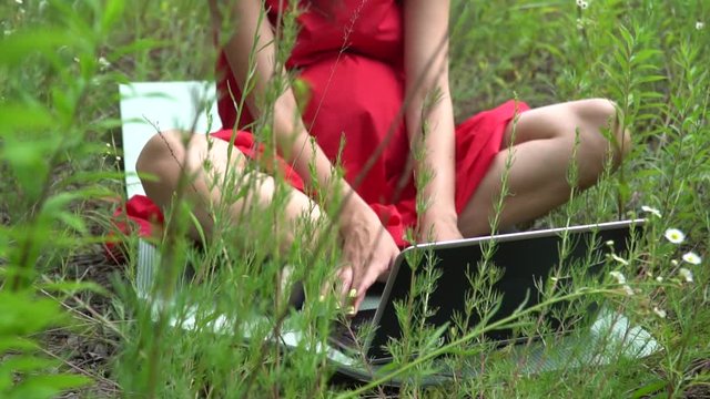 Young trendy woman typing keyboard. Girl using laptop outside.