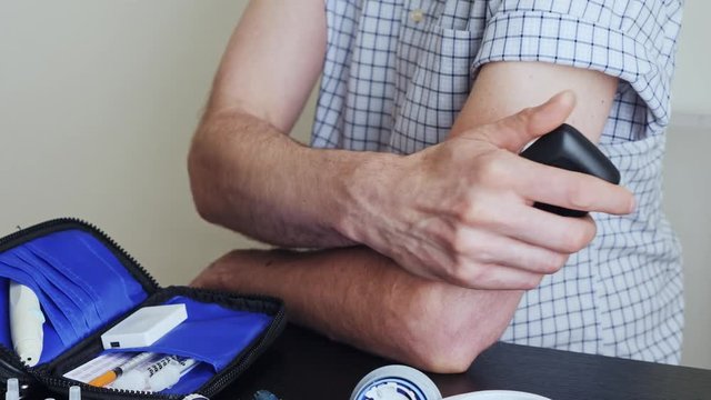 A man using a non-invasive glucose meter to measuring glucose level blood