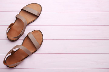Female beige sandals on pink wooden table