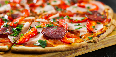 slices of Pizza with Mozzarella cheese, Ham, Tomatoes, salami, pepper, pepperoni Spices and Fresh Basil. Italian pizza