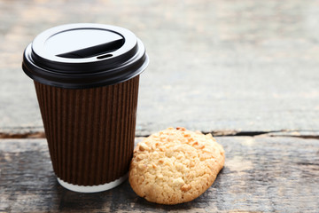 Paper cup of coffee with cookies on grey wooden table
