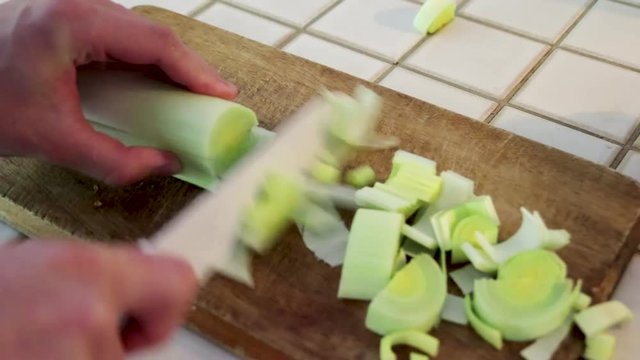 Cutting a leek on wooden board in kitchen, vegetable, 356% speed.