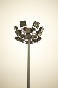 spotlight of soccer football stadium on gray steel pole with cloudy blue sky background , vertical image