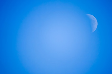 Crescent / half moon in the middle of the day with blue sky in the background.