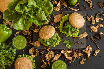 Fototapeta na wymiar Vegan burgers with beet cutlet and green smoothies on black background. Healthy vegan food. Detox diet.