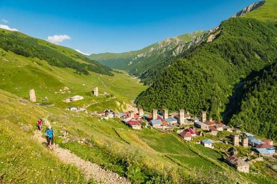 Girls hiking above Adishi village with Svan towers, Caucasus mountains, Mestia district, Georgia