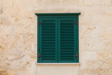 Closed wooden window on the facade of the old Italian home with yellow wall 