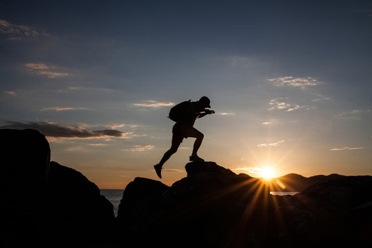 Man jumping on cliffs in sunset