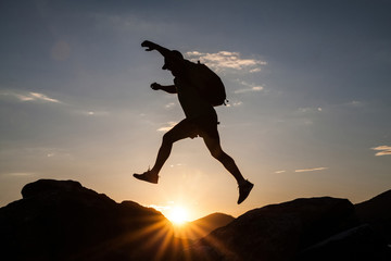Man jumping on cliffs in sunset