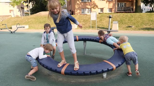 Many children have fun enjoy play and spin on outdoors playground in a city