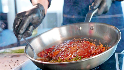 Meat steak with seasonings and herbs hissing on frying pan, close-up