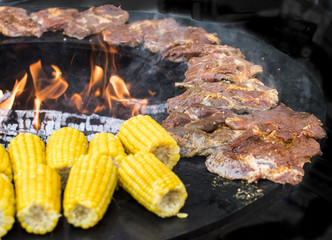 Grill mit offener Flamme rohen Steaks und Maiskolben