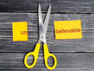 scissors cut the word unbelievable. concept believable. cuts the word 