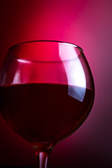 Glass with red wine on a dark red background