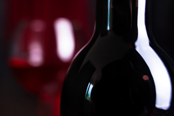 Wine. A glass and a bottle of red wine.. Red wine on a dark background.