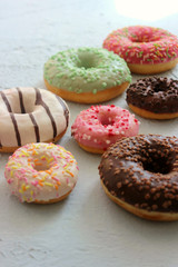 Photos of different donuts. Assorted colorful donuts in pink, green, chocolate icing close-up, sweet dessert.