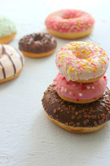 Photos of different donuts. Assorted colorful donuts in pink, green, chocolate icing close-up, sweet dessert.