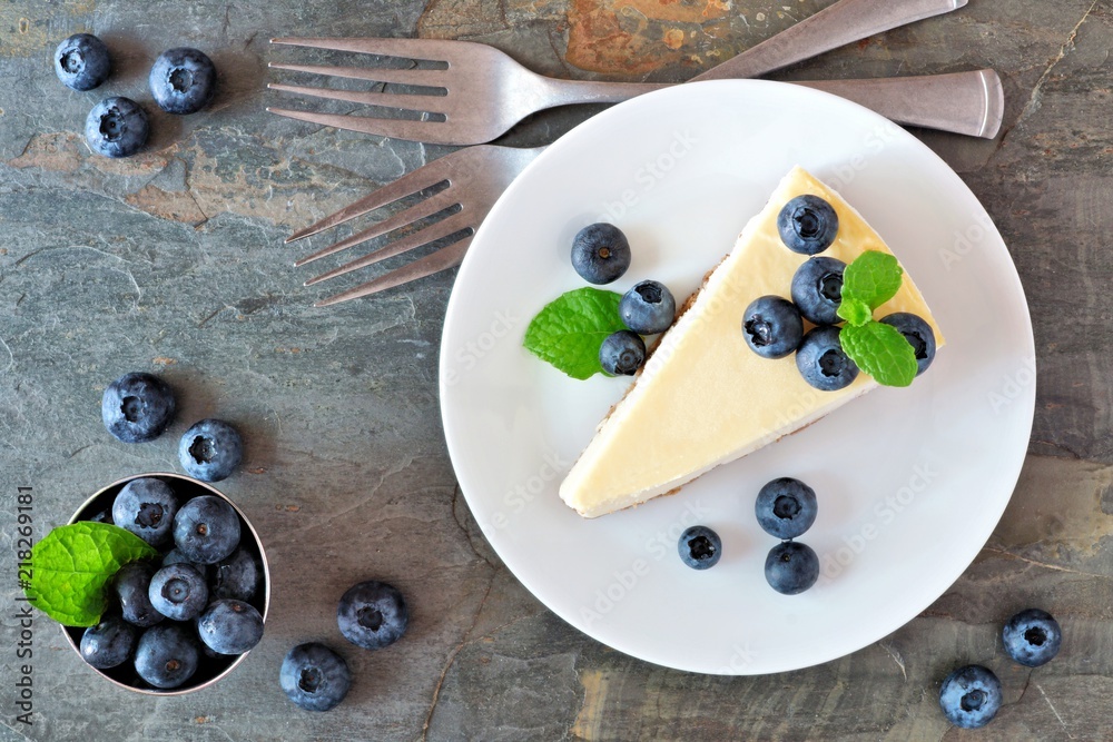 Poster slice of cheesecake with blueberries on a plate. top view scene over a dark background.