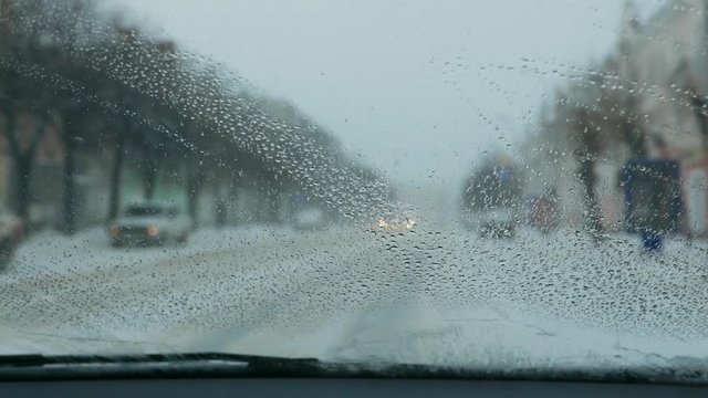 Car traffic in a blizzard, snowfall in the city. Bad non-flying weather. Automotive headlights. Low visibility.  Wet snow, icing on the windshield. Road safety