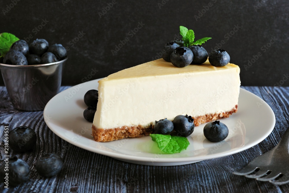Poster slice of cheesecake with blueberries. close up scene with a dark background.