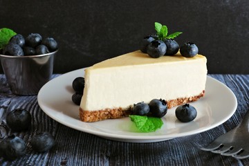 Slice of cheesecake with blueberries. Close up scene with a dark background.