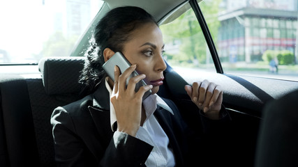 Attractive businesswoman sitting in taxi, talking on phone, serious conversation