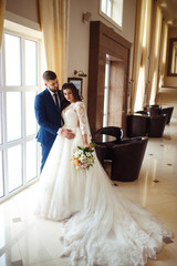 Fototapeta premium Beautiful Bride and Groom enjoy each other in the nice hall of the hotel. happy romantic young couple celebrating their marriage.Sexy kissing stylish couple of lovers close up portrait. wedding
