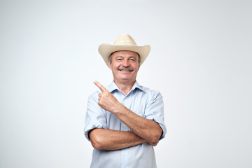 Your advertising here. Studio portrait of handsome senior man in blue shirt and cowboy hat showing copy space