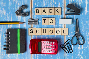 Back to school. Mini school supplies on blue wooden background.