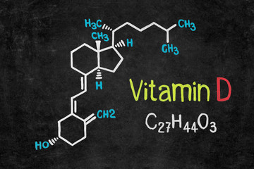 Handwritten chalk chemical formula of Vitamin D on school blackboard.
