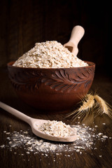 Dry flakes in a wooden bowl on a wooden background near the ears of wheat. wooden spoon with Dry flakes