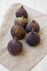 Fototapeta premium Fresh figs on cloth over white wooden surface, side view.