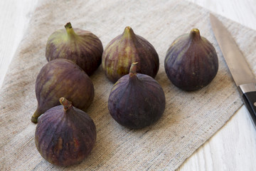 Obraz premium Fresh figs with knife on cloth over white wooden surface, side view.