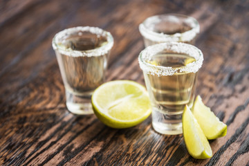 Tequila and lime slices in the defocus on a wooden background in the bar