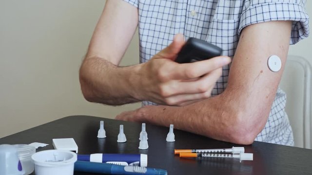A man brings to the hand the reading device to the sensor for measuring glucose