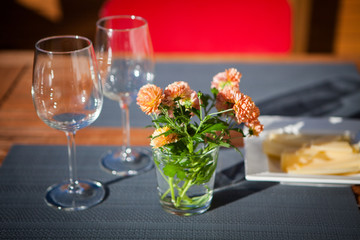 A glass with wildflowers and two empty glasses on a gray napkin on a wooden table in the street