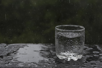 Naklejka na ściany i meble Summer rain filling a glass with water