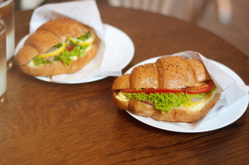 Two fresh croissant sandwiches with tomato and hum