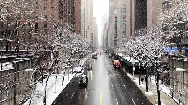 Tilt Up Shot of Snow Falling Over Buildings and Street in Midtown
