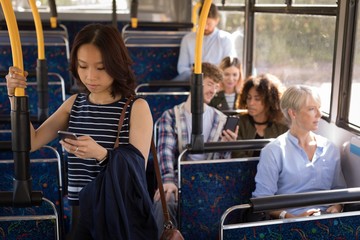 Female commuter using mobile phone while travelling in modern