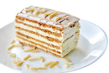 Sweets, cake, traditional hungarian,austrian cuisine. Esterhazy cake sliced on white background. Sweet tasty dessert on white round plate with  almond. Close-up served. Isolated on white background.