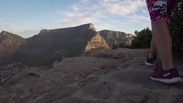 Girl walking on top of Lions Head towards Table Mountain in Cape Town, South Africa during Sunset, in Slow Motion