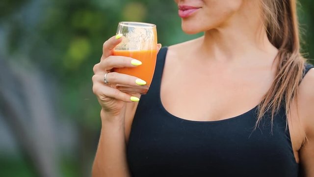 Adult woman drinking orange juice in a garden, healthy lifestyle concept