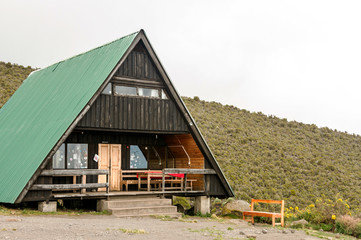 Fototapeta na wymiar Mountain cabin with deck on a hillside with clouds