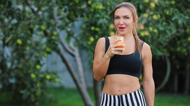 Adult woman drinking orange juice in a garden, healthy lifestyle concept