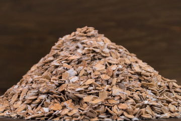 Oat flakes, sprinkled with a slide on the table, close-up, wooden background.