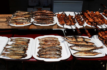 fish whole grilled on a grill and meat on skewers cooked entirely on an open fire lie on white trays on the embankment near the Black Sea. Reportage shooting. Republic of Crimea