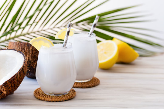 Coconut cocktail in glasses with lemon and drinking straw. White background. Copy space