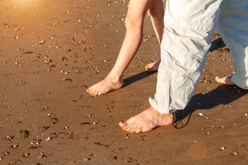 dad and son walk on the beach barefoot